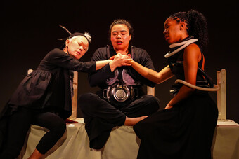Three people on stage holding hands in the center.
