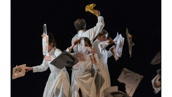 actors in white onstage mid-performance.