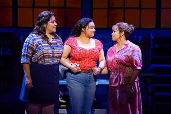 Three women on stage holding hands.
