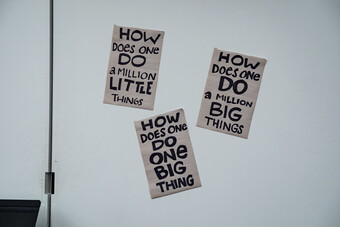 A wall with three signs on brown paper.