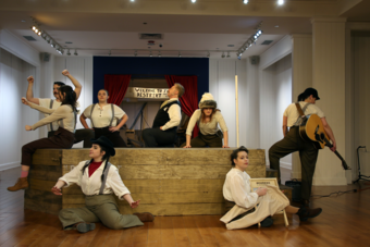 A group of people in old timey clothes posing around a set.