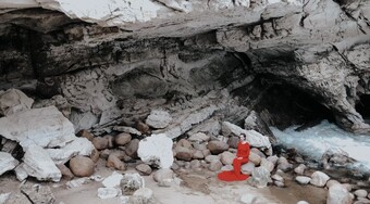 A woman in a long red dress in a rocky area.