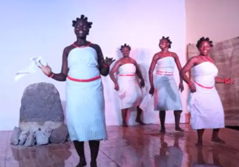 Four people in white cloth dresses on stage.