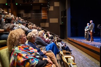 A large audience watching two people on stage.