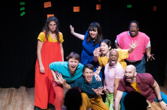 A group of people make expressive faces onstage.