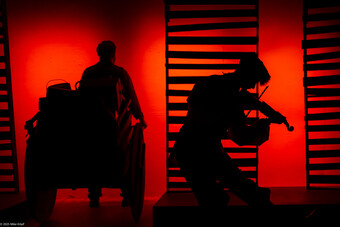 A person plays a violin in silhouette.