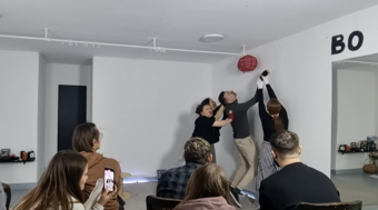 A group of people push up a balloon in a corner.