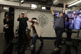 A group of people dance in front of a screen.