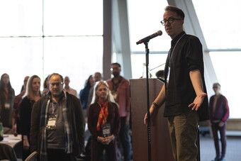 A person addresses a room on a microphone.