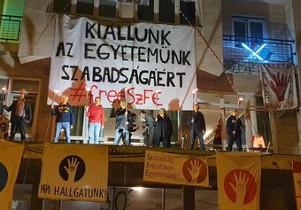 A group of people stand on a balcony surrounded by protest signs.