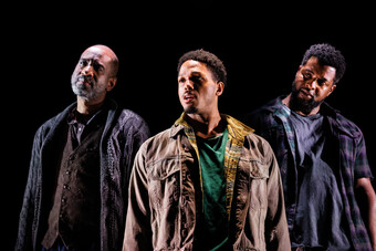 Three men stand onstage.