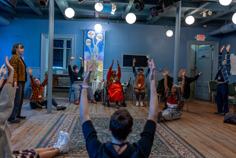 A group of people sit in a circle with their arms raised.