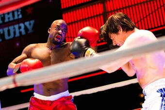 Two actors fight on stage in a boxing ring in Rocky.