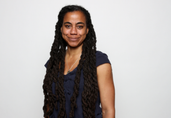 Portrait of Suzan-Lori Parks smiling at the camera against a blank background.