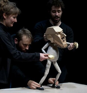 Three performers control a puppet of a man.