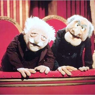 The Muppet characters Statler and Waldorf leaning over the railing of a theater box.