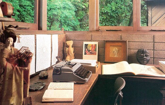 A messy writer's desk with a journal and a typewriter.