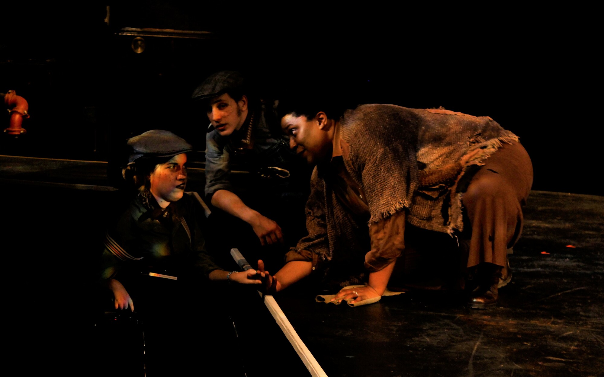 four actors in costume crouching onstage
