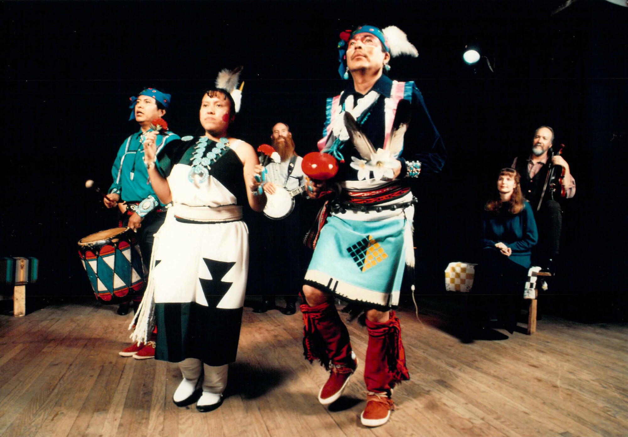three performers in traditional Native American costume