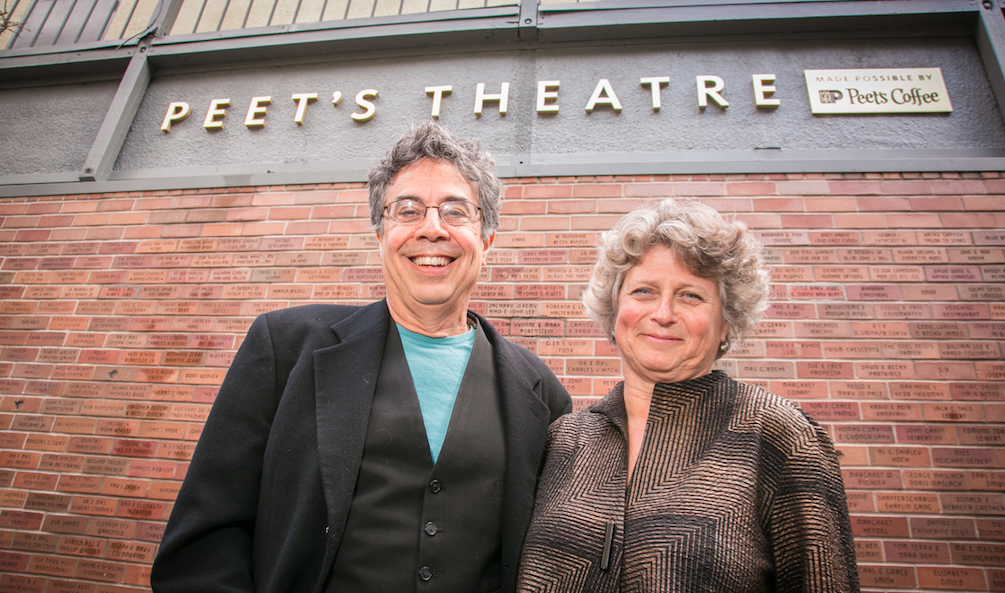 Two people smiling in front of a theatre