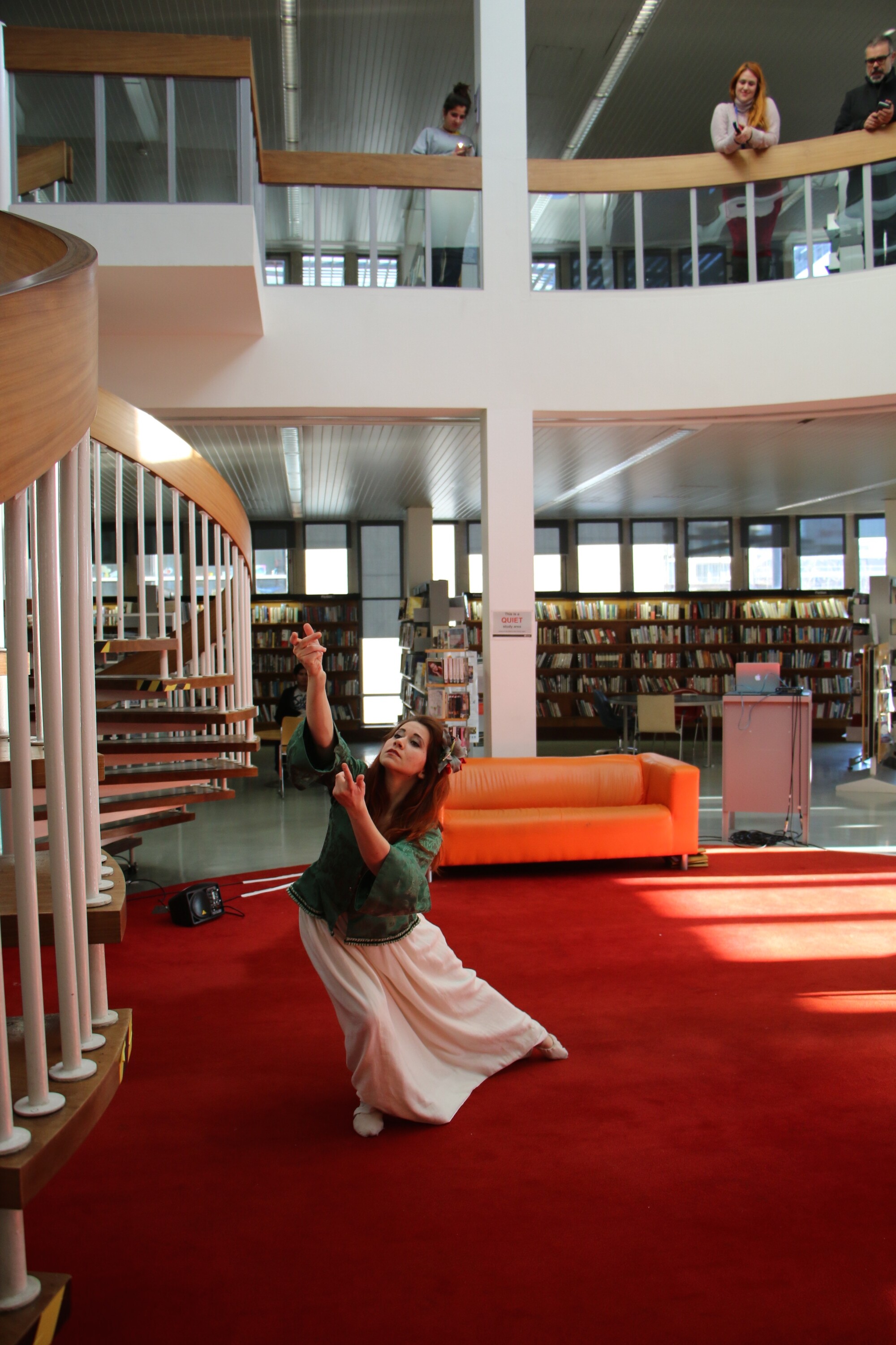performer dances in a library while audience members watch