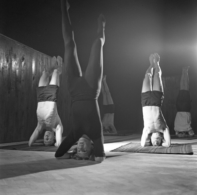 Black and white image of three people standing on their heads
