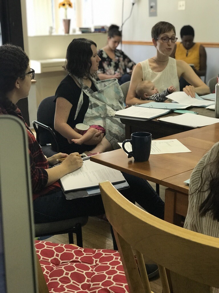 people sitting around a rehearsal table holding babies