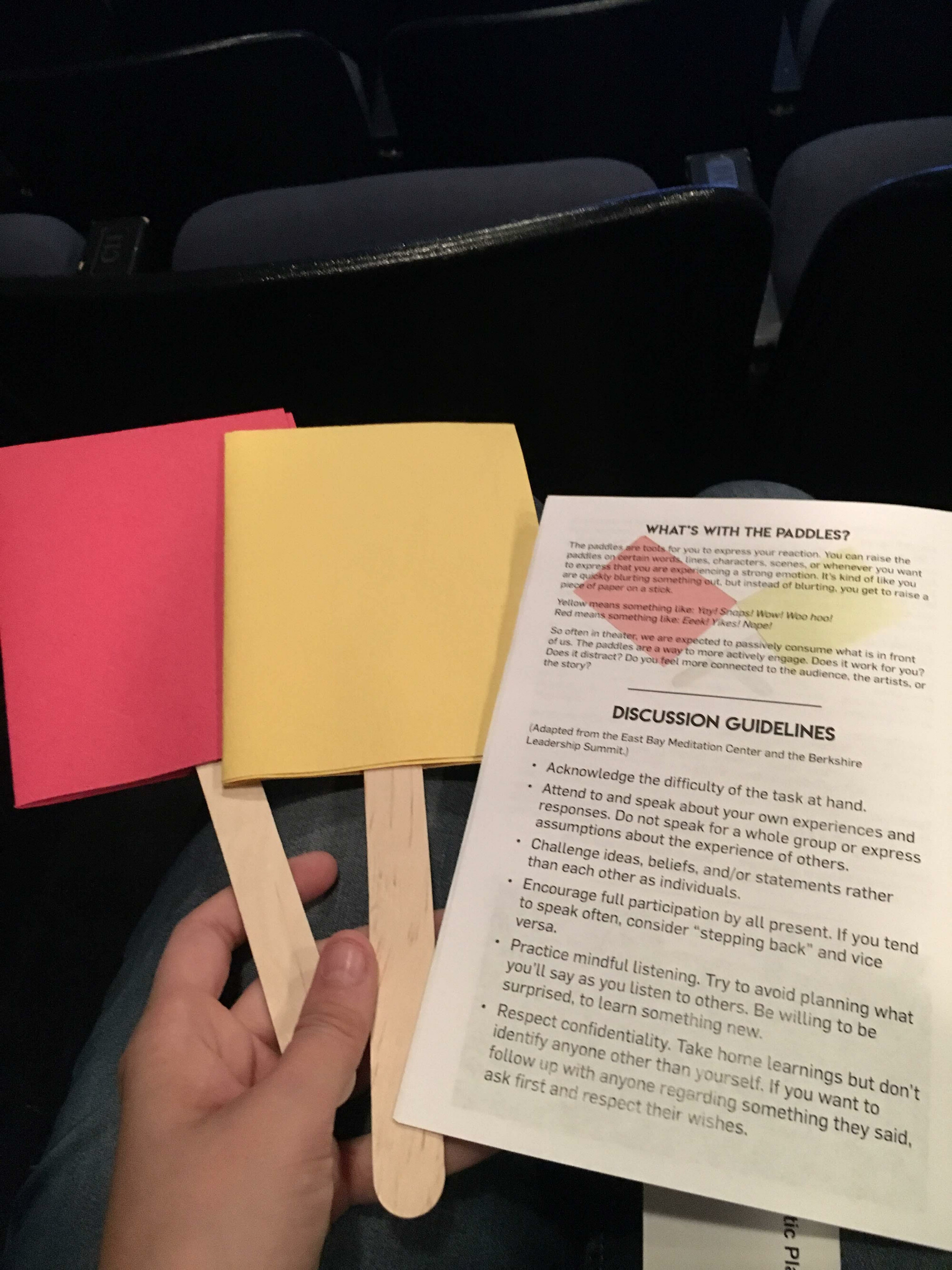 hand holding two paddles and a sheet with discussion guidelines