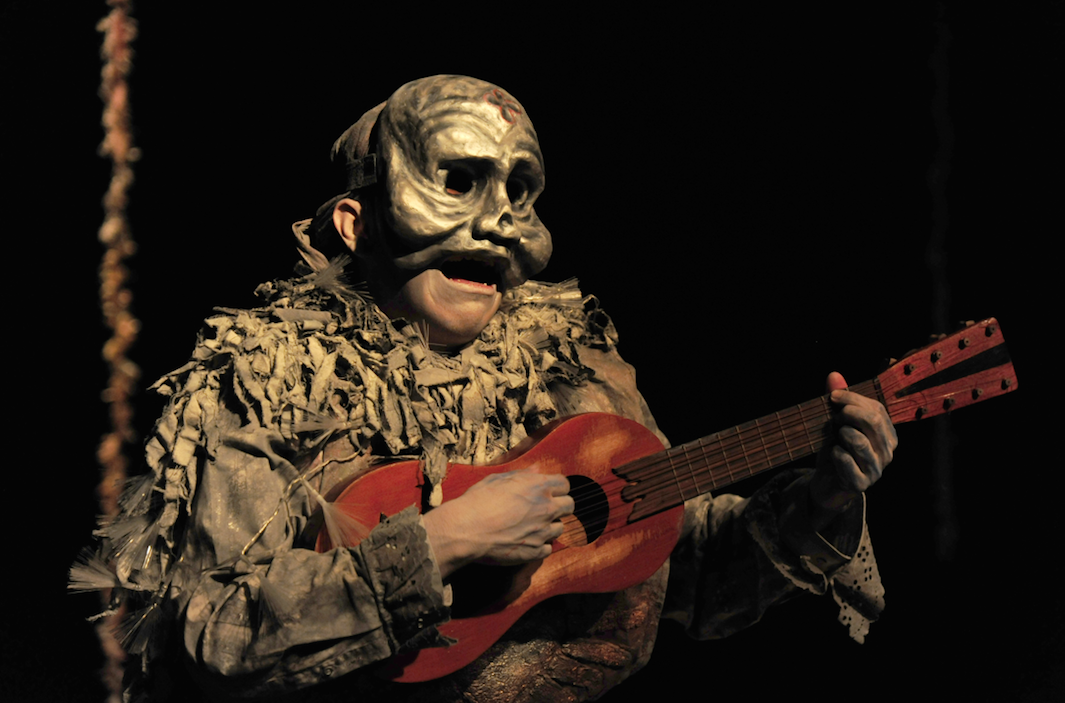 masked performer playing the guitar 
