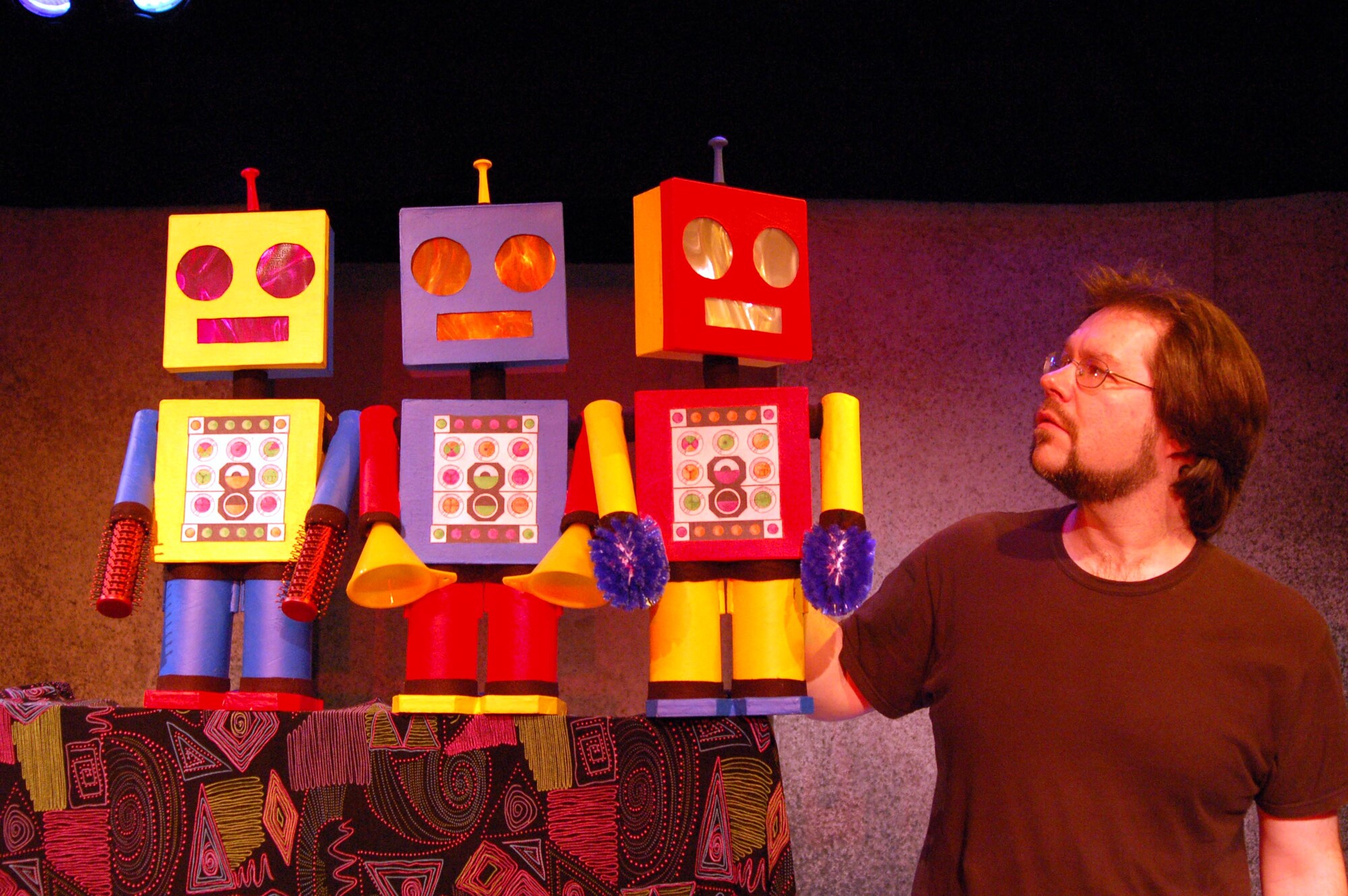an actor onstage with three robot props