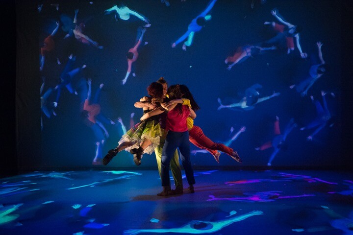 two dancers embrace around projection