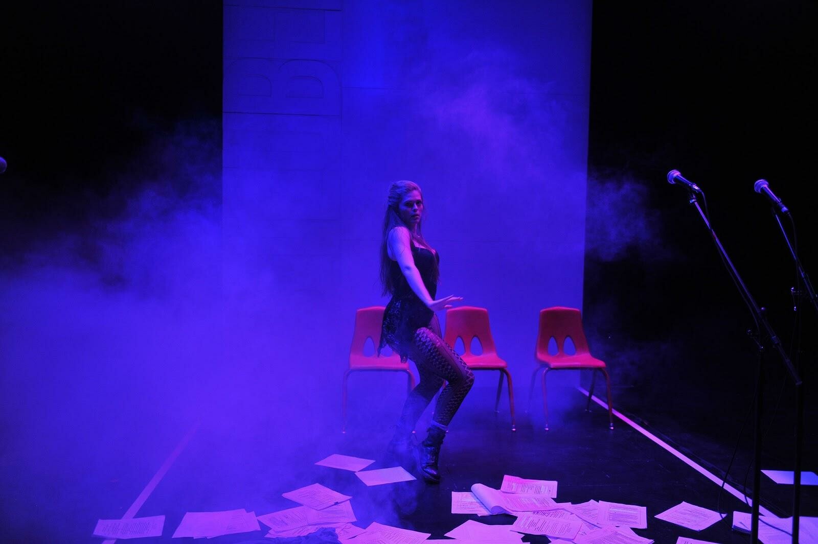 performer in foggy blue light dancing in front of chairs