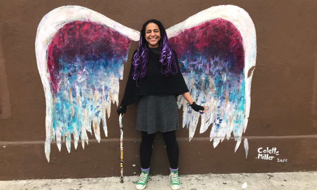 a person in front of a colorful angel wings mural