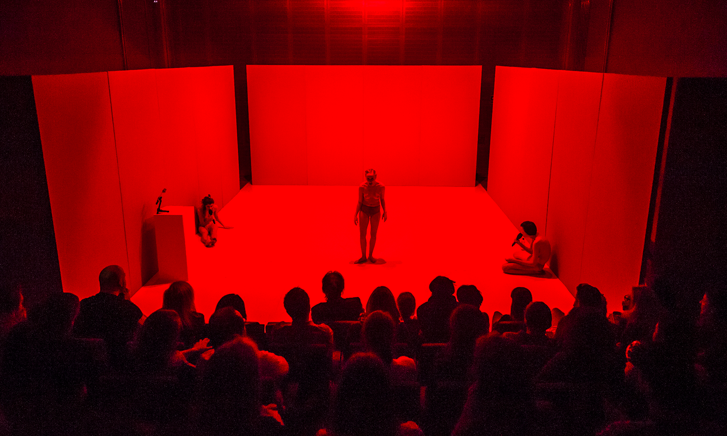 three actors onstage in red lighting