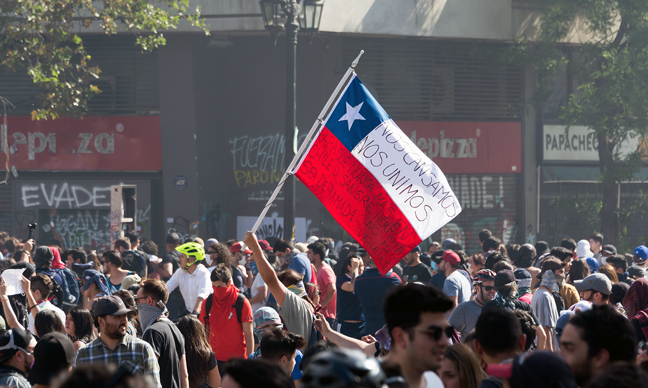 a large group of protesters with a Chilean flag