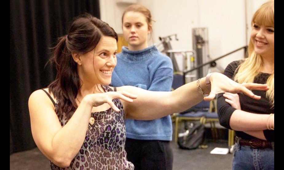 Intimacy Director Tonia Sina expressing an idea with her arms and hands in a rehearsal with two actors