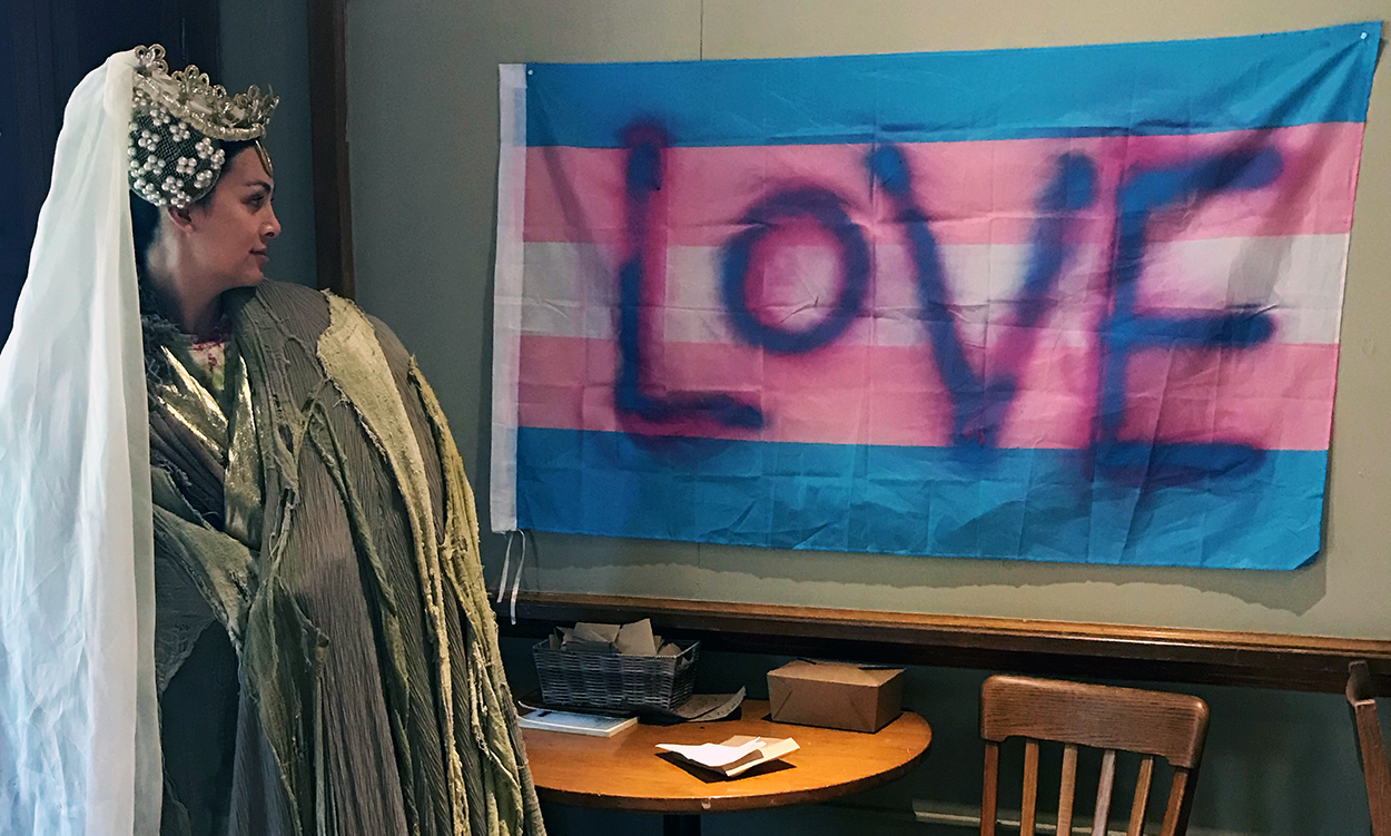 an actor posing with a trans pride flag with "love" written upon it