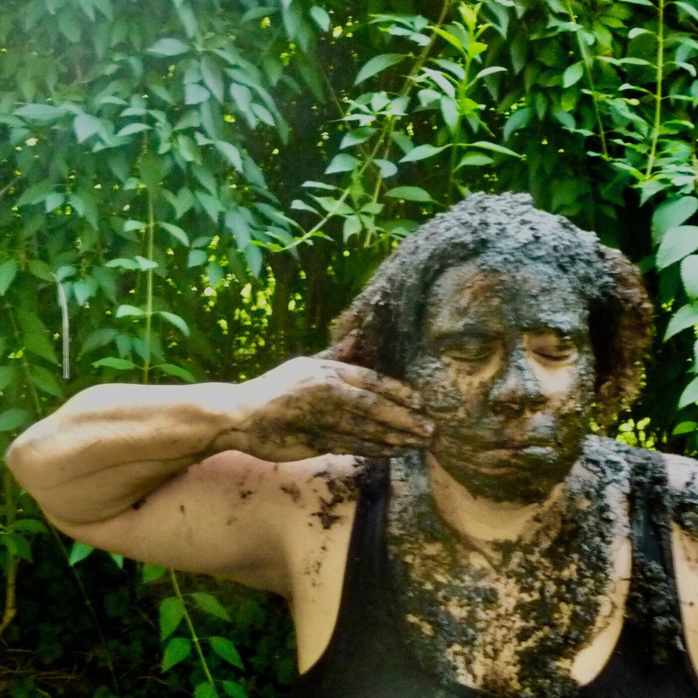 A woman of color smearing mud on her face