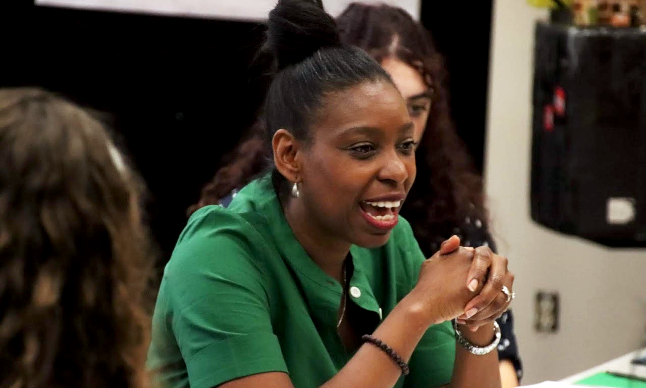 tamilla woodard in a green blouse seated and talking