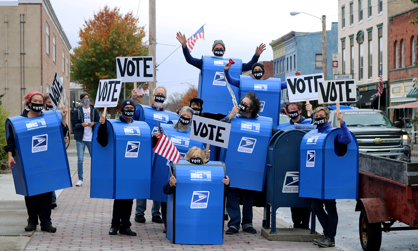 a group dressed as blue US mailboxes posing for a photo