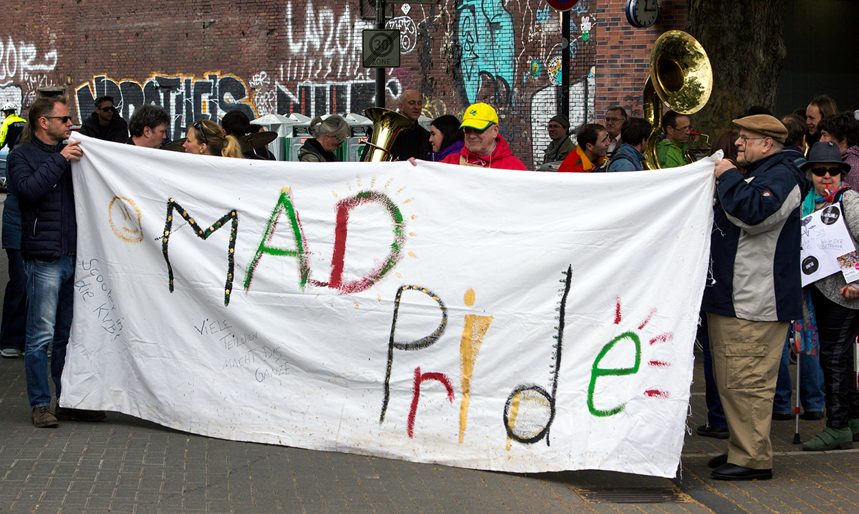 a group of people holding a banner saying "MAD Pride"