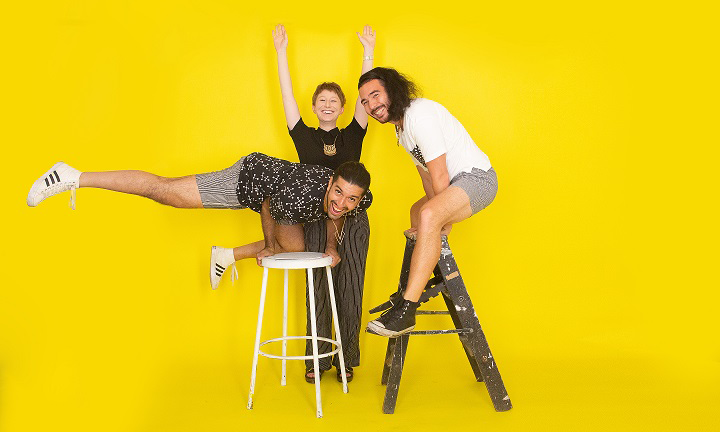 three people posing for a photo in front of a yellow backdrop