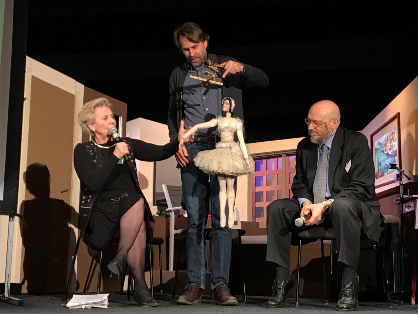 A presentation during the Puppet Theatre conference in Salzburg, Austria, 2020. Philippe Brunner (center), director of the Salzburg Marionette Theatre, displays one of the oldest puppets in the company’s collection, while Barabara Heuberger (left) describes the figure’s history and significance, joined onstage by Piero Corbella (right).