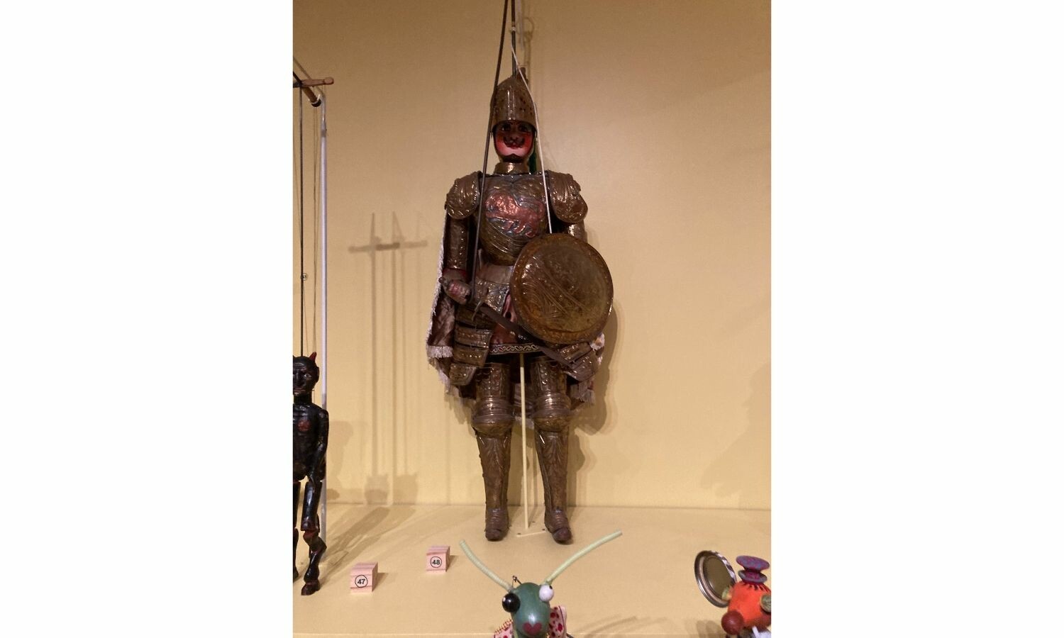 A puppet knight dressed in bronze with a matching bronze shield.