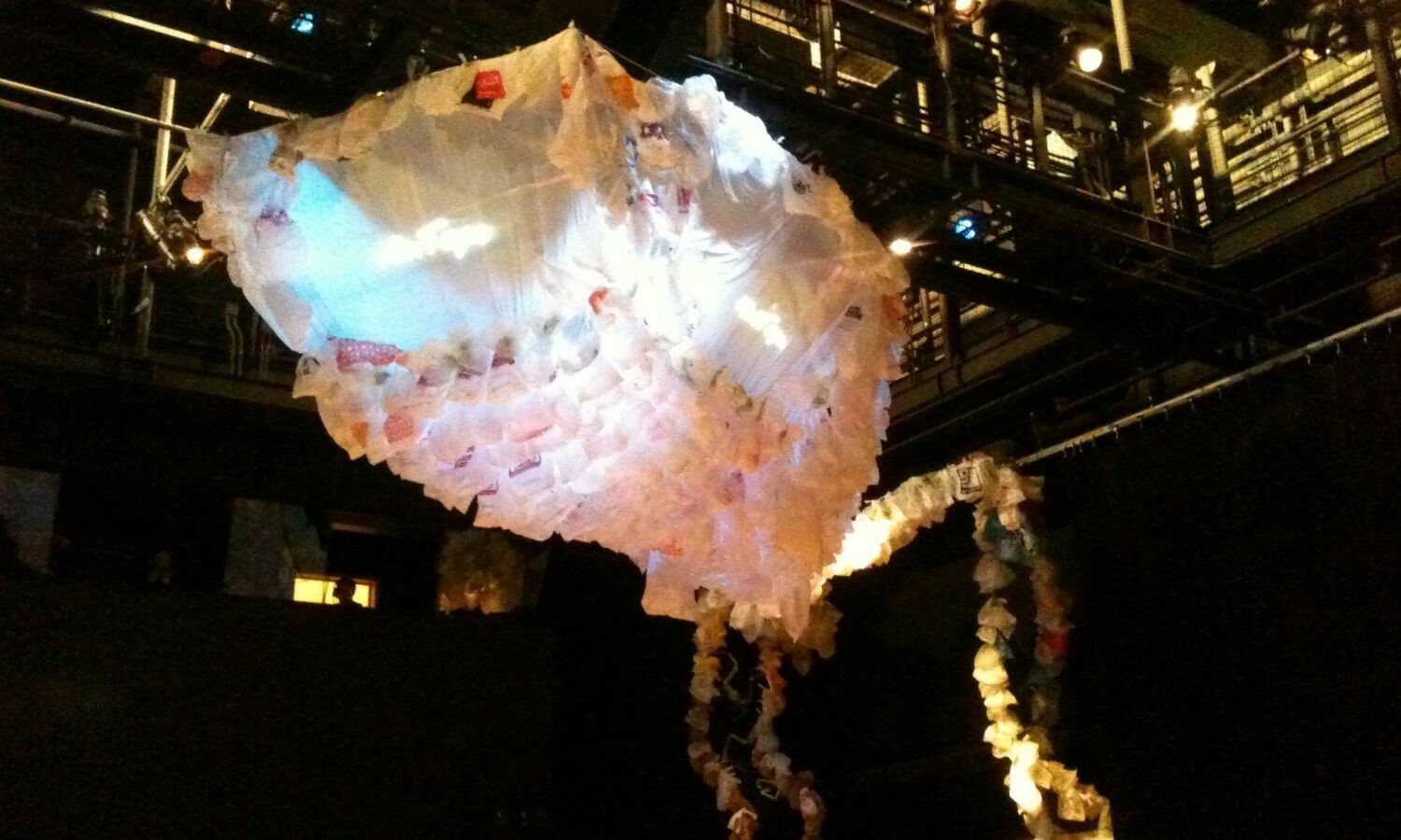 A floating jellyfish-like figure made out of a large sheet and plastic bags.