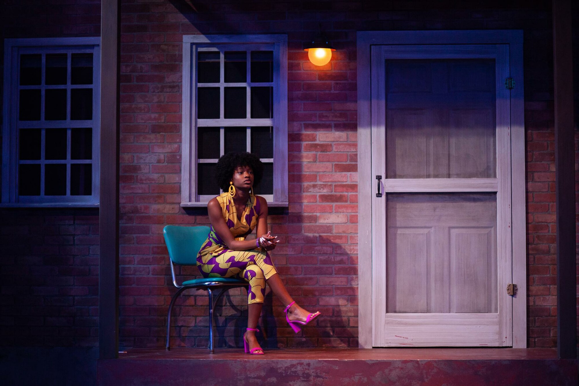 Image of Black woman with afro sitting in front of a door. 