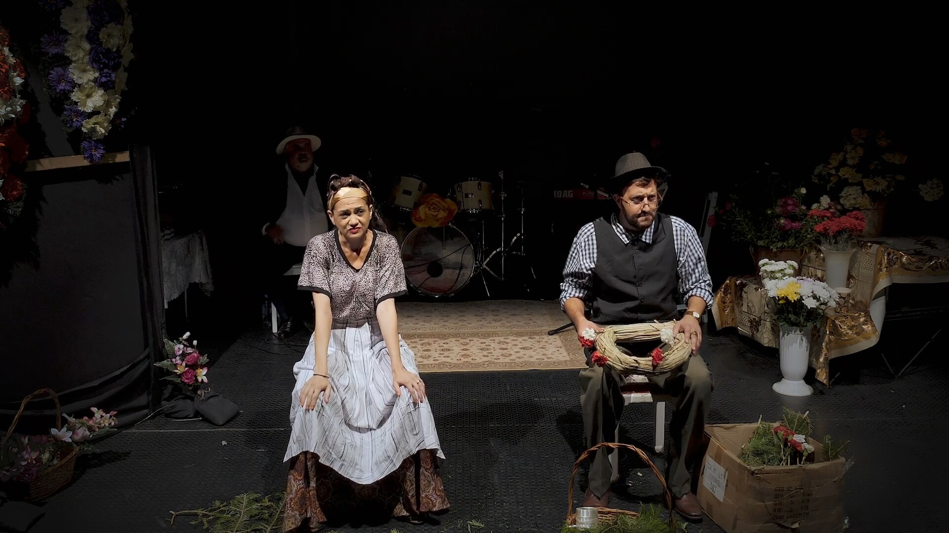 A woman and a man in vintage clothing sitting on stage.