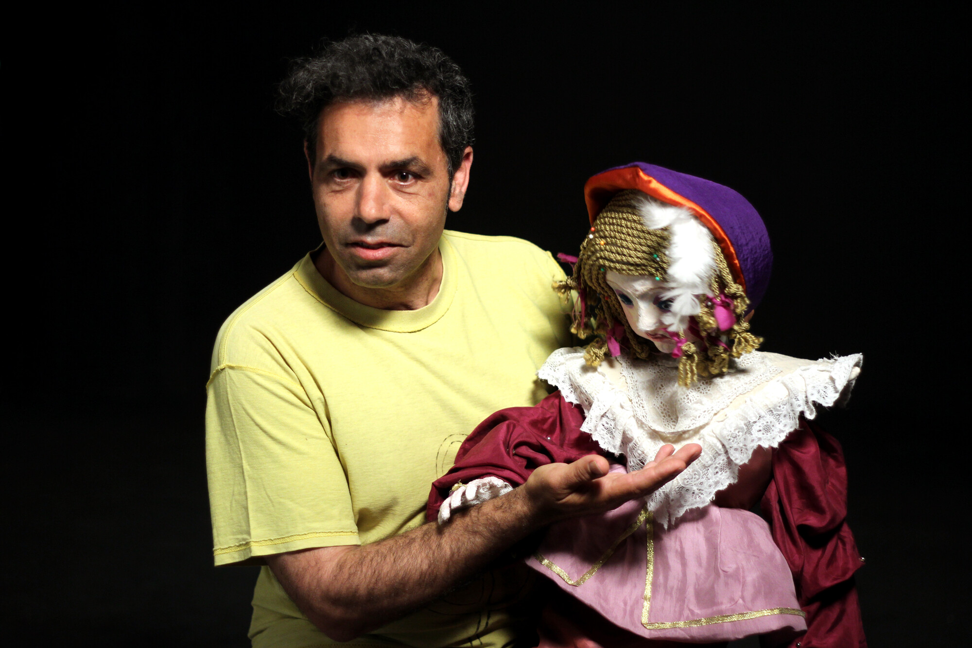 A man holding a puppet resembling a little girl.