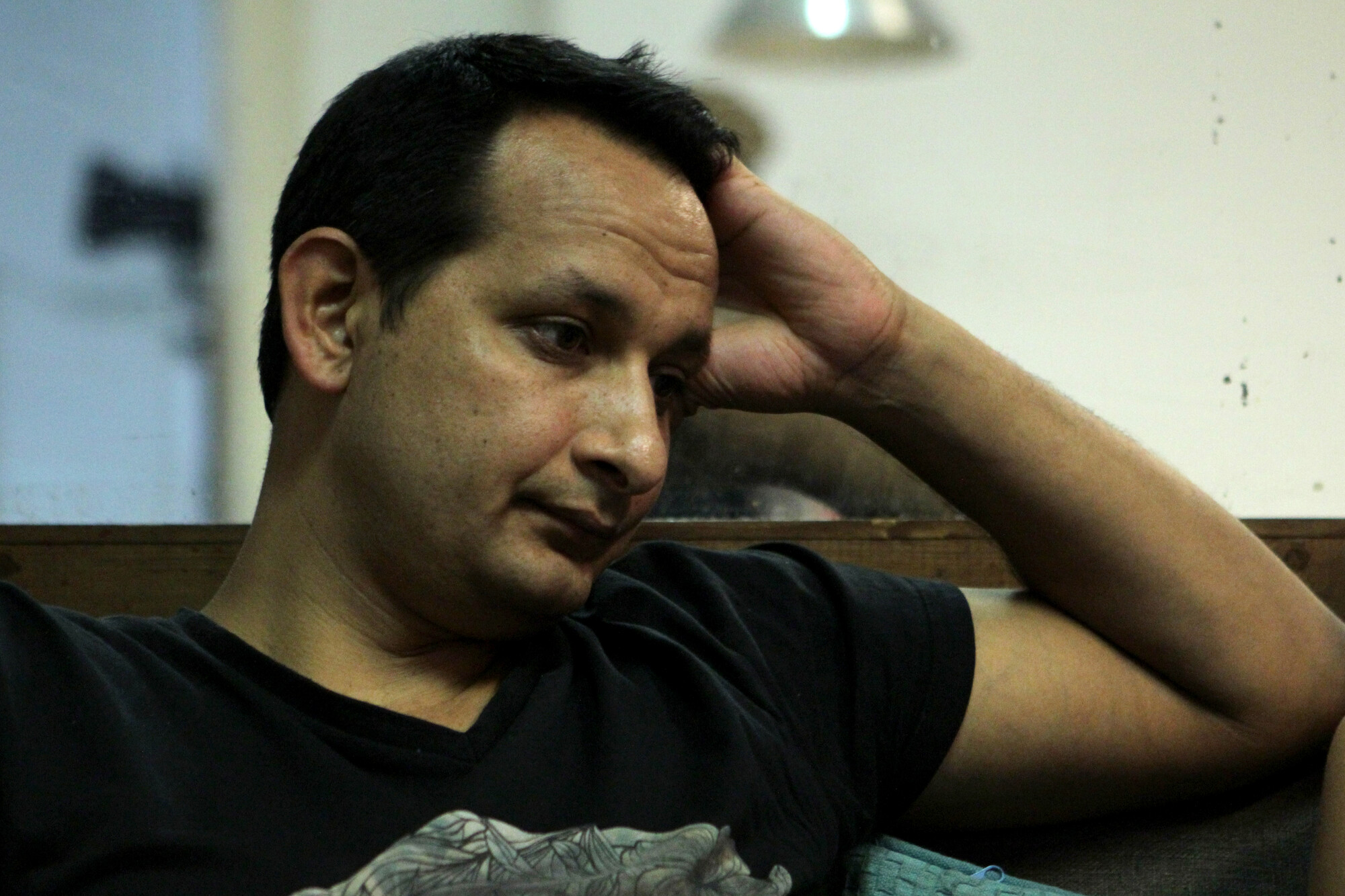 Man in black shirt resting his head in his hand. 