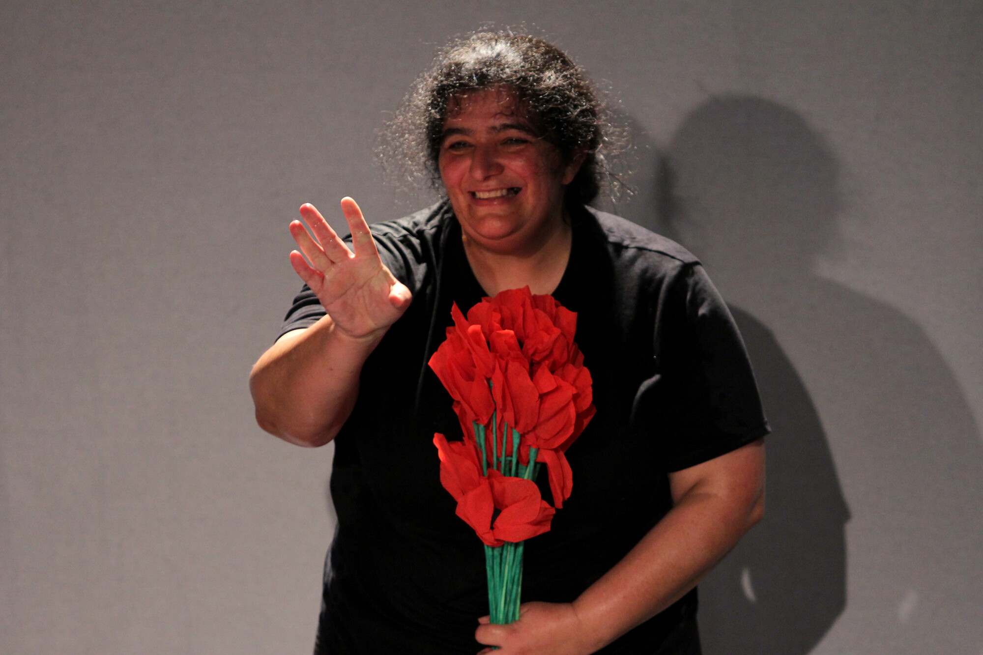 A woman holding red flowers and smiling.